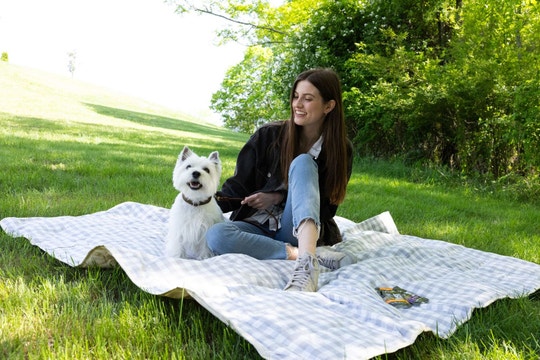 Woman sitting on a blanket in a park with a cute Westie