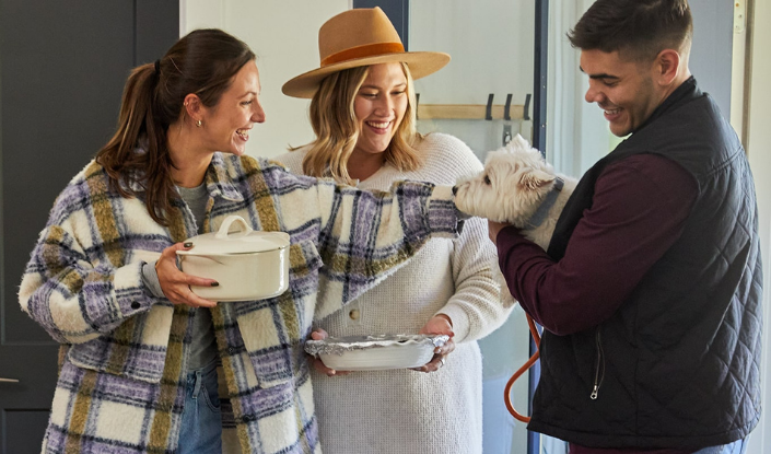 People holding and petting a West Highland White Terrier 