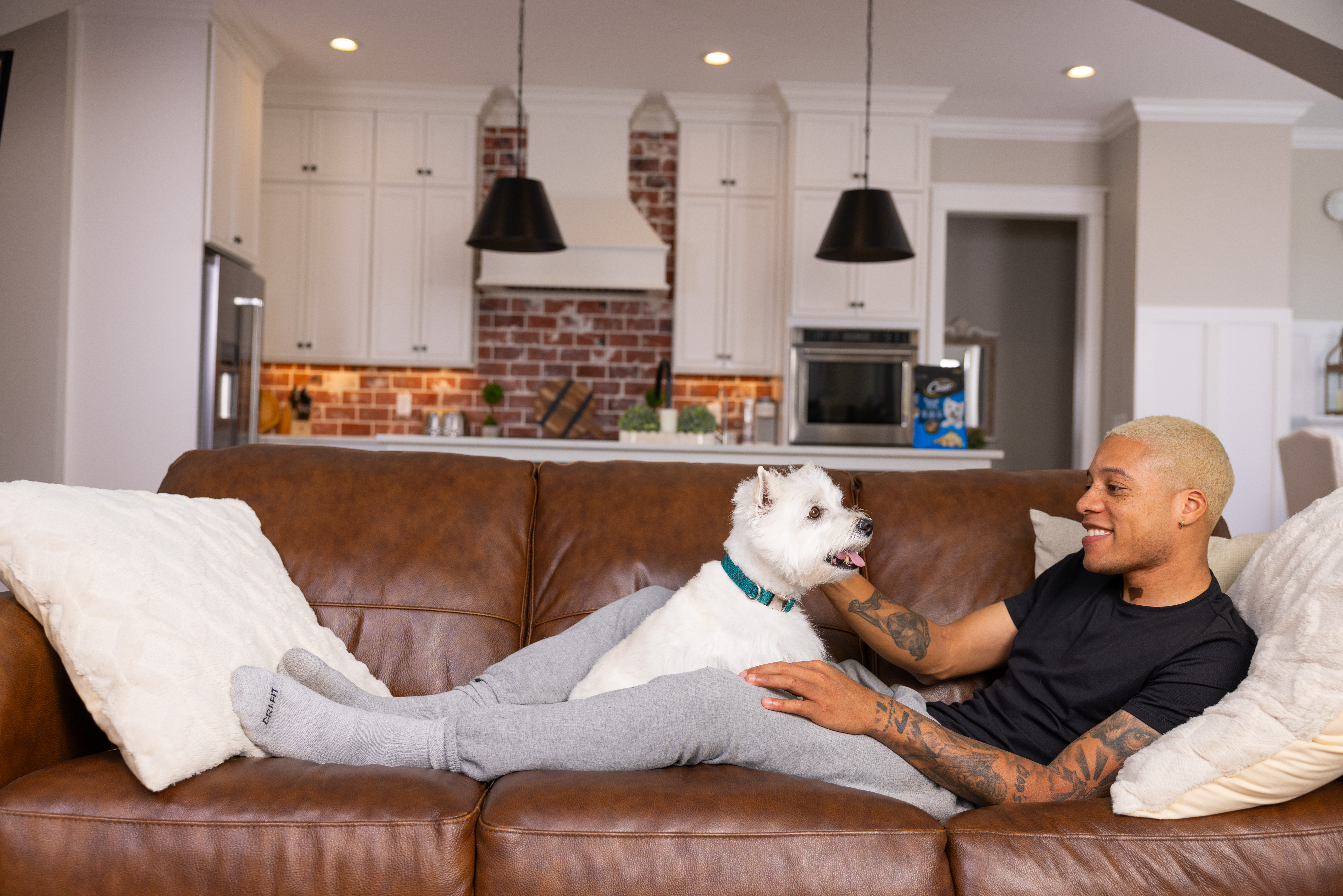 Pet parent relaxing on couch with his Westie.