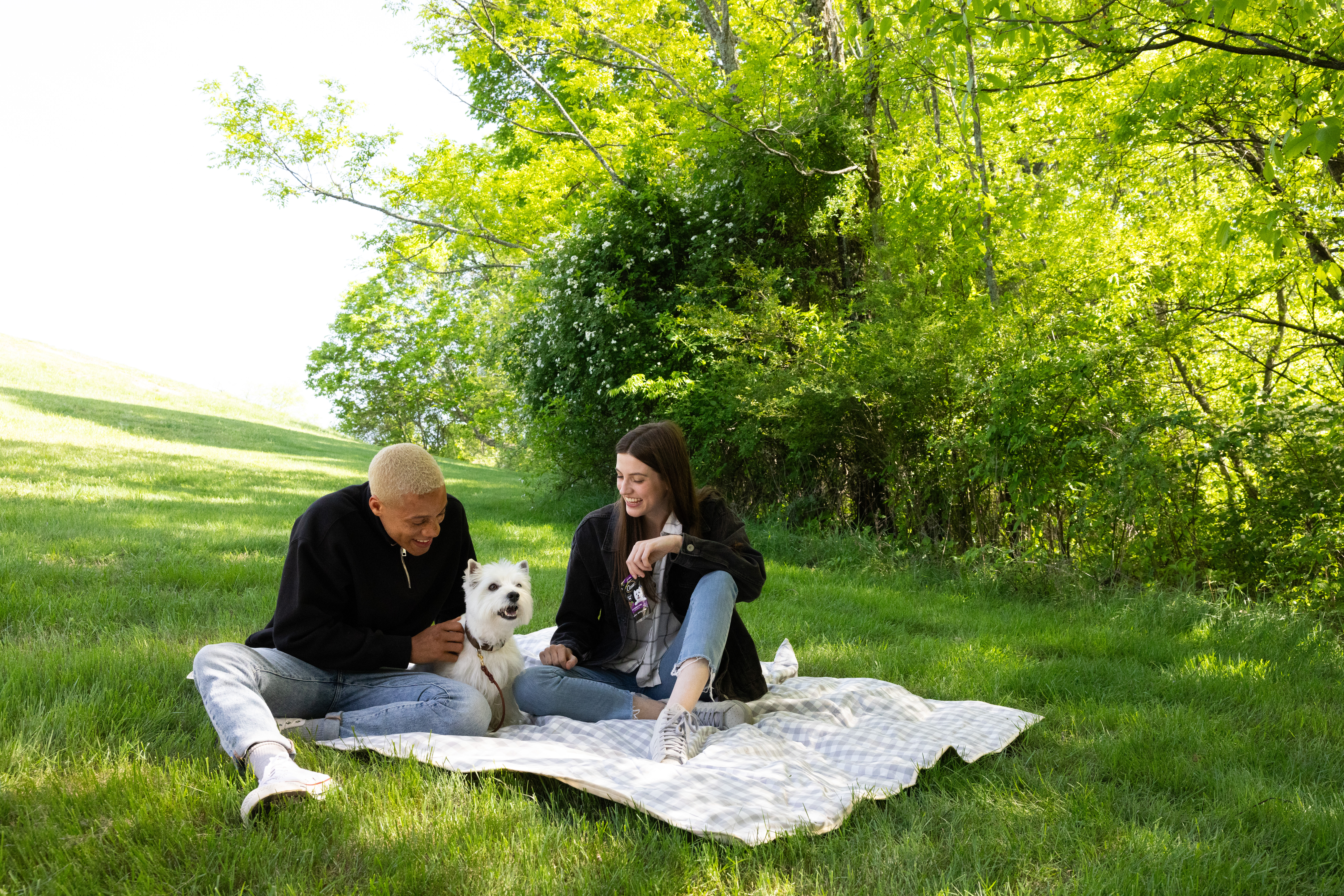 Two pet parents bonding with their Westie at the park